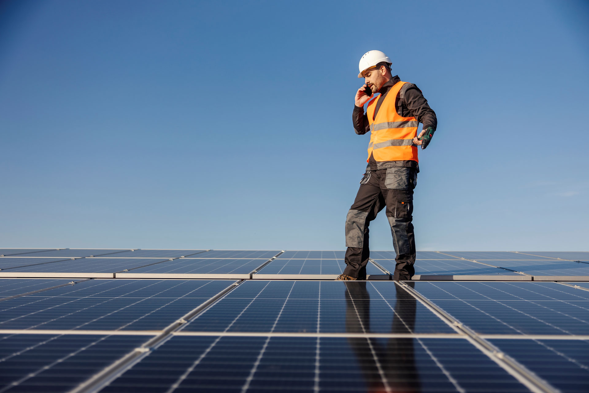 Mann mit Warnweste auf Solarpanels